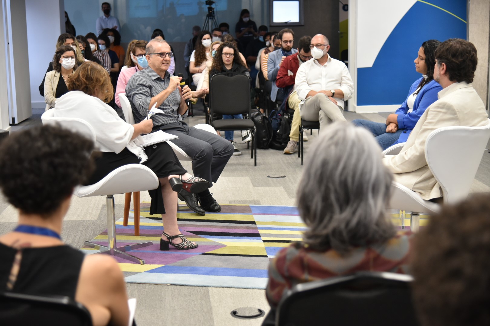  Imagem com fundo azul escuro, com grafismos no canto inferior direito que formam os elos do logo do Instituto Unibanco